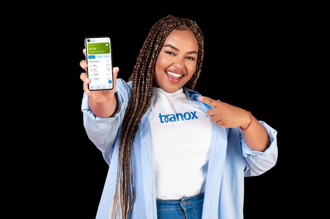 Une cliente Tranox souriante montrant du doigt l'application Tranox ouverte sur son téléphone