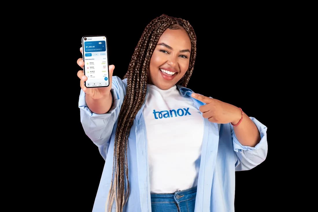 A Tranox customer smiling and pointing at the Tranox app open on her phone